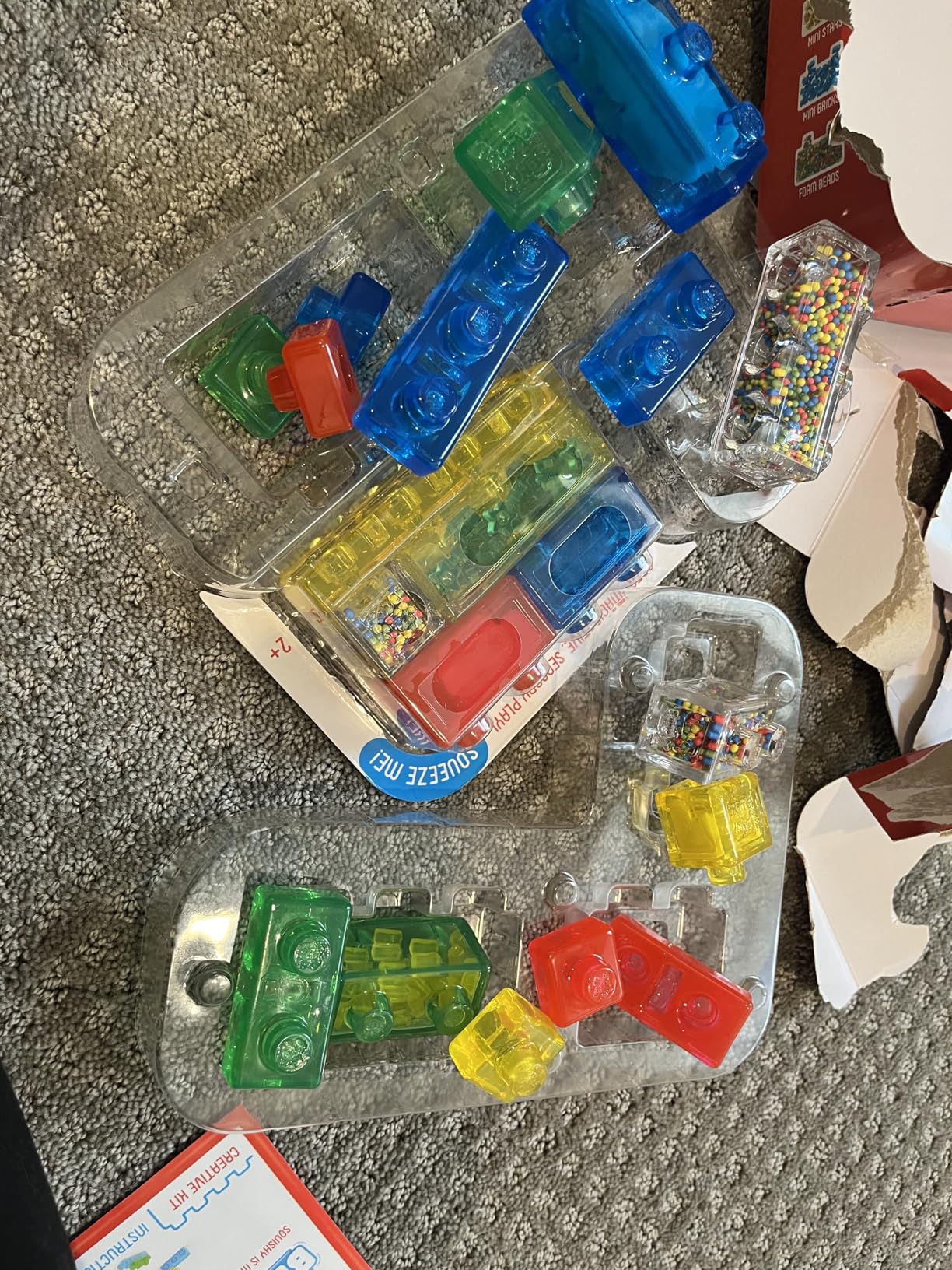 Creative Kit tray opened on gray carpet, foam-bead and mini-brick filled blocks still in the plastic insert