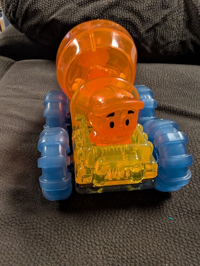 Built Jelly Blox cement mixer with an orange worker in the seat, photographed on a dark couch